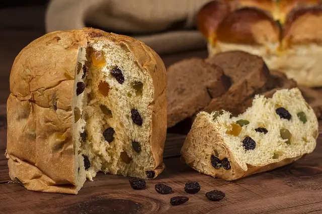A panettone with raisins and candied fruit with a cut slice