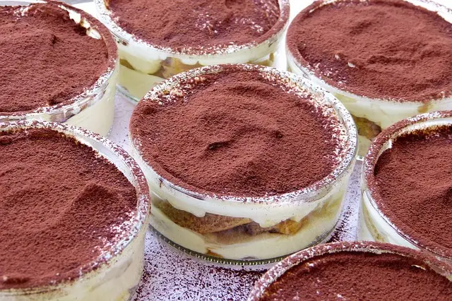 Glass ramekins of individual tiramisù dusted with cocoa powder